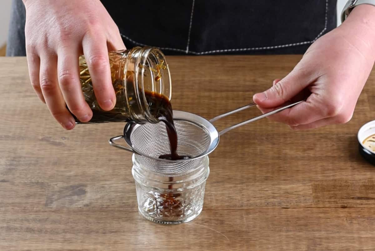 pouring ponzu sauce through strainer.