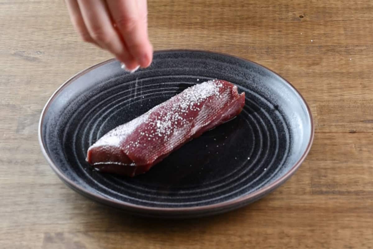 seasoning venison backstrap with salt.