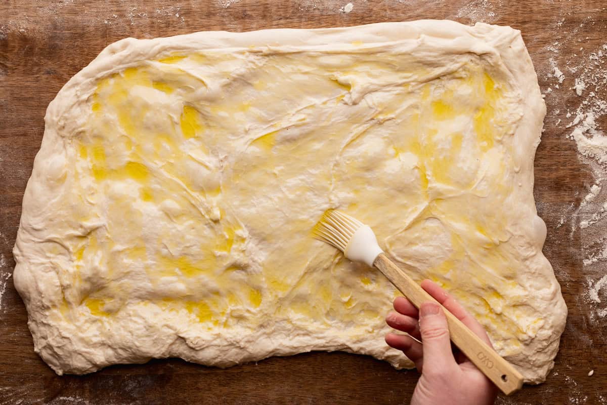 brushing olive oil on sourdough dough rectangle.