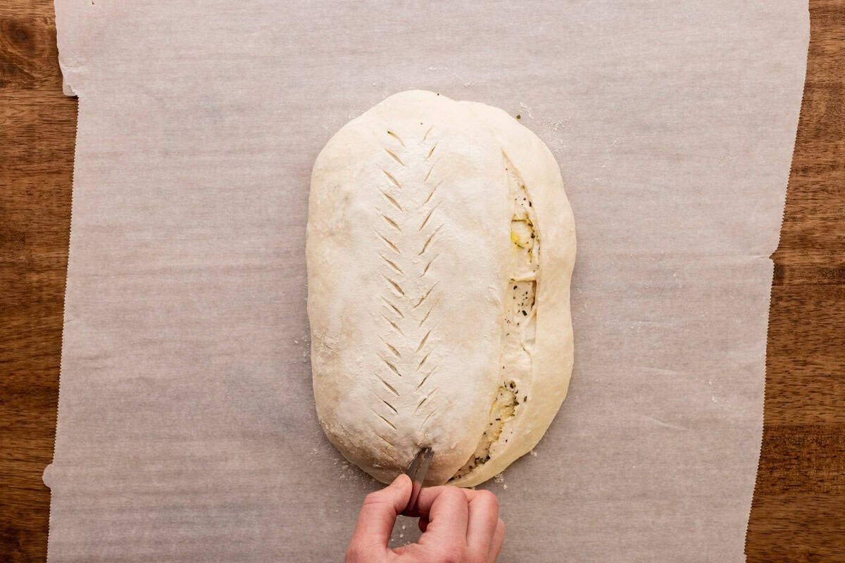 cutting decorative slits into sourdough loaf.