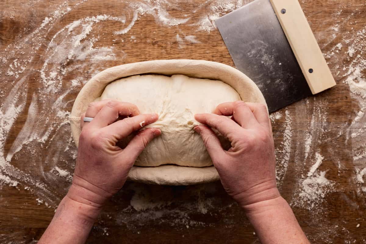 pinching seam of sourdough loaf in banneton.