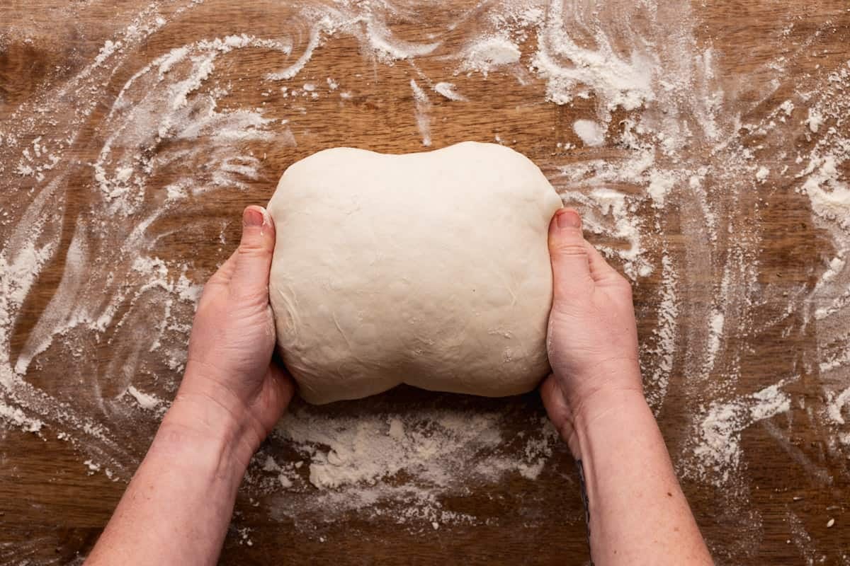 rolling sourdough into loaf with hands.